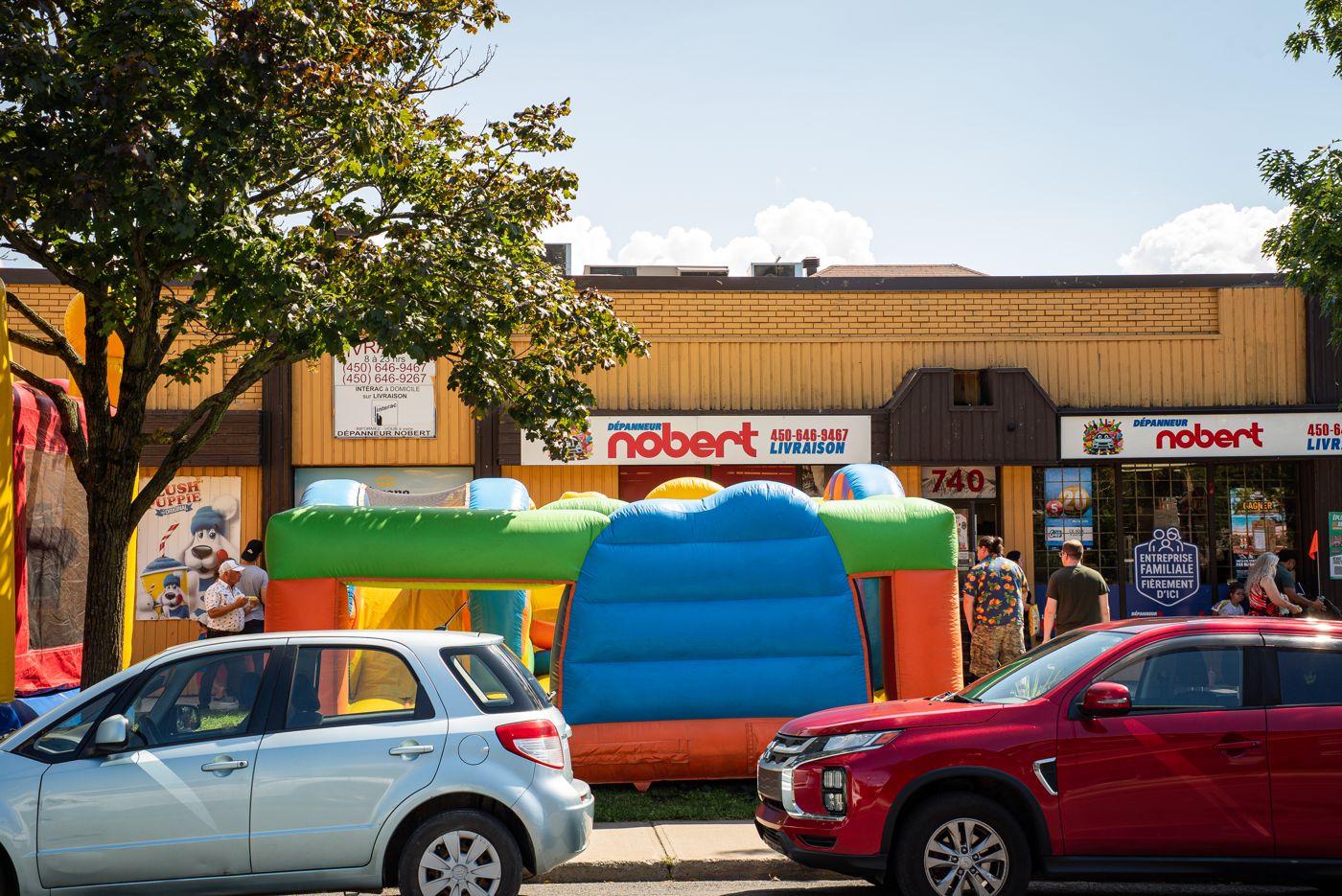 Jeux gonflables et foule devant le Dépanneur Nobert pendant l'épluchette